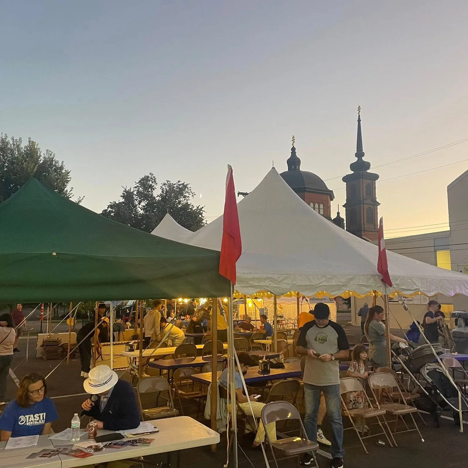 Evening tents and string lights with the cathedral towers behind